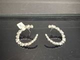 deux paires de boucles d'oreilles créoles en argent posées sur une surface noire