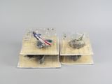 deux boîtes contenant chacune un avion miniature, posées sur une surface grise