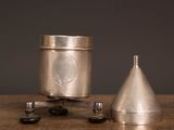 a small metal object sitting on a table next to a cup