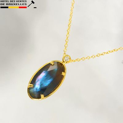 a close up of a necklace with a blue stone on a gold chain