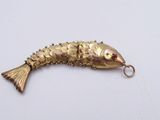 an image of a gold fish pendant with a red stone in the mouth
