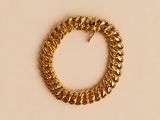 un bracelet en chaîne d'or avec un fermoir, sur fond beige