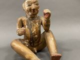 an old wooden figurine of a man sitting on the ground