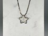 a silver necklace with a star pendant on a white marble surface