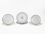 three porcelain plates and saucers with gold rims on a white background