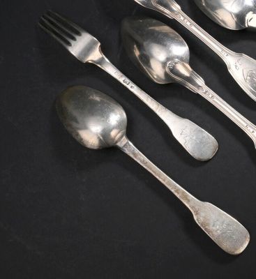 quatre cuillères en argent et une fourchette posées sur un fond noir