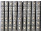 six old books are lined up in a row on a white surface