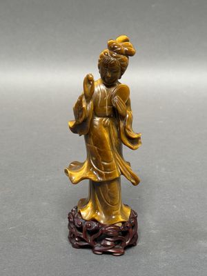 une statue antique en bronze représentant une femme tenant une fleur