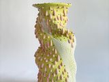 un vase vert orné de petites taches roses et jaunes