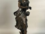 une statue antique en bronze représentant une femme tenant un panier de fleurs