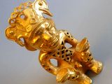 a gold figurine with a bird on top of it