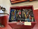une boîte à outils rouge remplie d'outils divers, posée par terre
