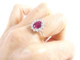 a woman ' s hand holding a ring with a ruby stone on it