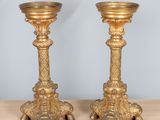 pair of antique brass candlesticks on wooden table against blue wall