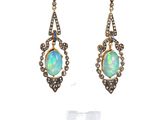 une photo d'une paire de boucles d'oreilles en oplite et en diamant
