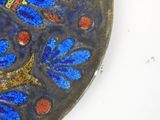 a close up of a blue and red plate with a bird on it