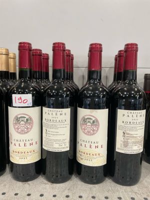 bottles of red wine are lined up on a shelf in a store