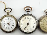 trois types différents de montres de poche sont présentés sur une surface blanche