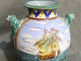 un vase sur lequel est peint un bateau, posé sur une table