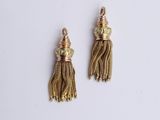 une paire de boucles d'oreilles à pompons dorés sur fond blanc