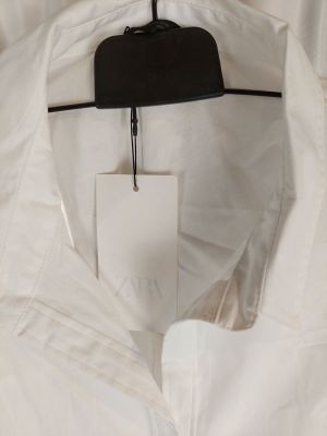 a white shirt hanging on a hanger in a room