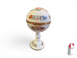 a white egg with a floral design on it on a pedestal