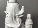 a figurine of a woman sitting on a tree stump with a bird perched on it