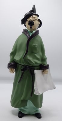 une figurine représentant un homme vêtu d'une robe verte et tenant un morceau de papier