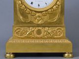 a gold clock with a white face on a stand