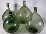 trois vases en verre vert posés sur une surface blanche