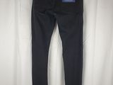 a pair of black jeans hanging on a hanger in front of a white curtain