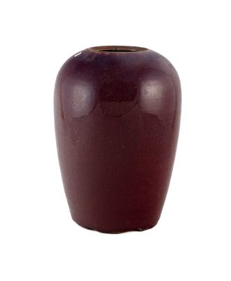 un vase rouge posé sur une surface blanche