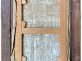 an old picture frame with a torn window and a piece of wood