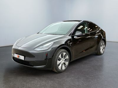 une Tesla Model Y noire garée dans une pièce aux murs blancs