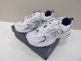 des chaussures New Balance blanches posées sur une boîte, elle-même posée sur une table