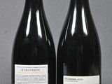 two bottles of red wine sitting next to each other on a table