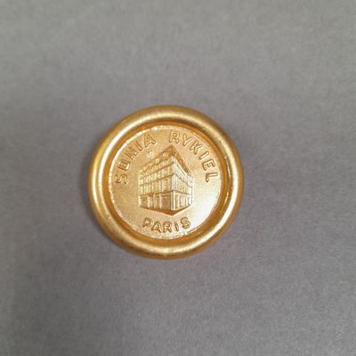 SONIA RYKIEL, PARIS. Pin's en métal doré et siglé présentant…