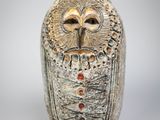 une figurine de chouette posée sur une surface blanche