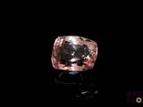 a pink diamond on a black surface with a black background