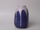 un vase bleu orné de motifs blancs, posé sur une surface blanche