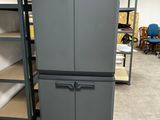 a gray refrigerator in the middle of a room with shelves