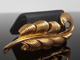 a gold feather brooch on a black surface