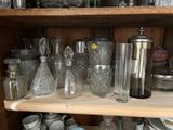 une étagère remplie de verre et d'objets en verre disposés sur les étagères