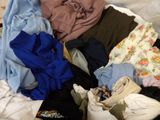 a pile of clothes that is on a bed