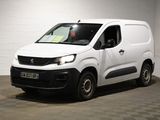 La petite camionnette blanche est garée dans une grande pièce.