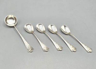 six cuillères et un repose-cuillère posés sur un plan de travail gris