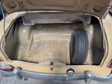 a tan car with its trunk open on the side of the road
