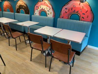 de nombreuses tables et chaises dans un restaurant dont les murs sont décorés de beignets peints