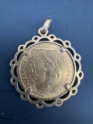 a silver coin pendant with a woman ' s face on it