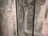 une porte de douche en verre dans un coin de la salle de bains